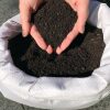 Regenwurmhumus Bodenverbesserer torffrei 4,5 kg Regenwurmhumus in einem geöffneten Beutel präsentiert von zwei Händen