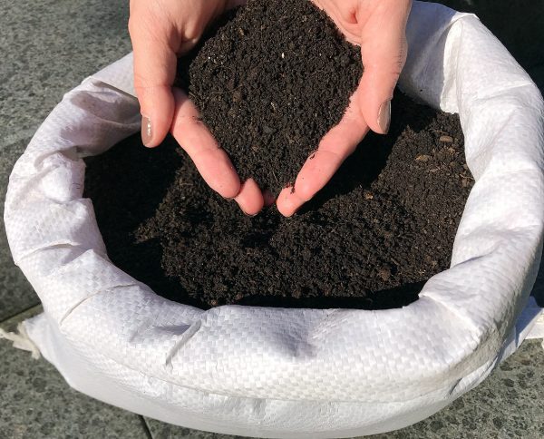 Regenwurmhumus Bodenverbesserer torffrei 4,5 kg Regenwurmhumus in einem geöffneten Beutel präsentiert von zwei Händen