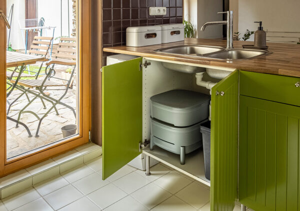 Wurmbox einem geöffneten Küchenschrank Wurmbox grau aus Recycling Kunststoff unter einer Spüle